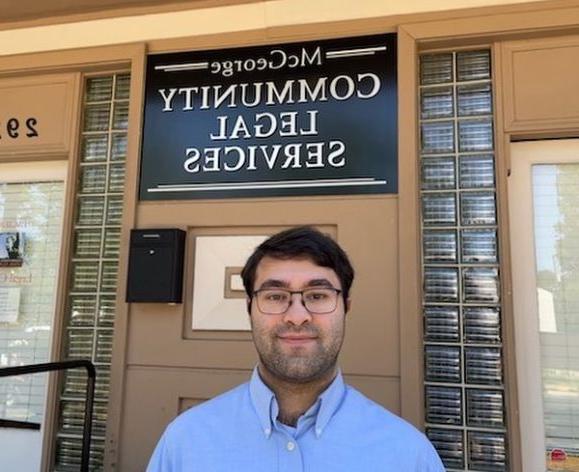 A man poses for a photo outside of a building